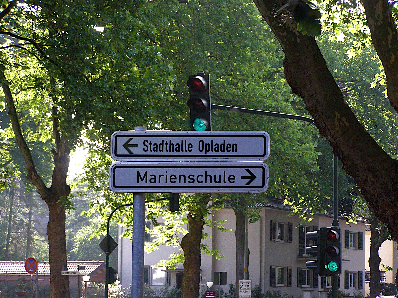 Ein weißer Straßenwegweiser für Autofahrer, das die Richtung zur Marienschule und der Stadthalle Opladen anzeigt.