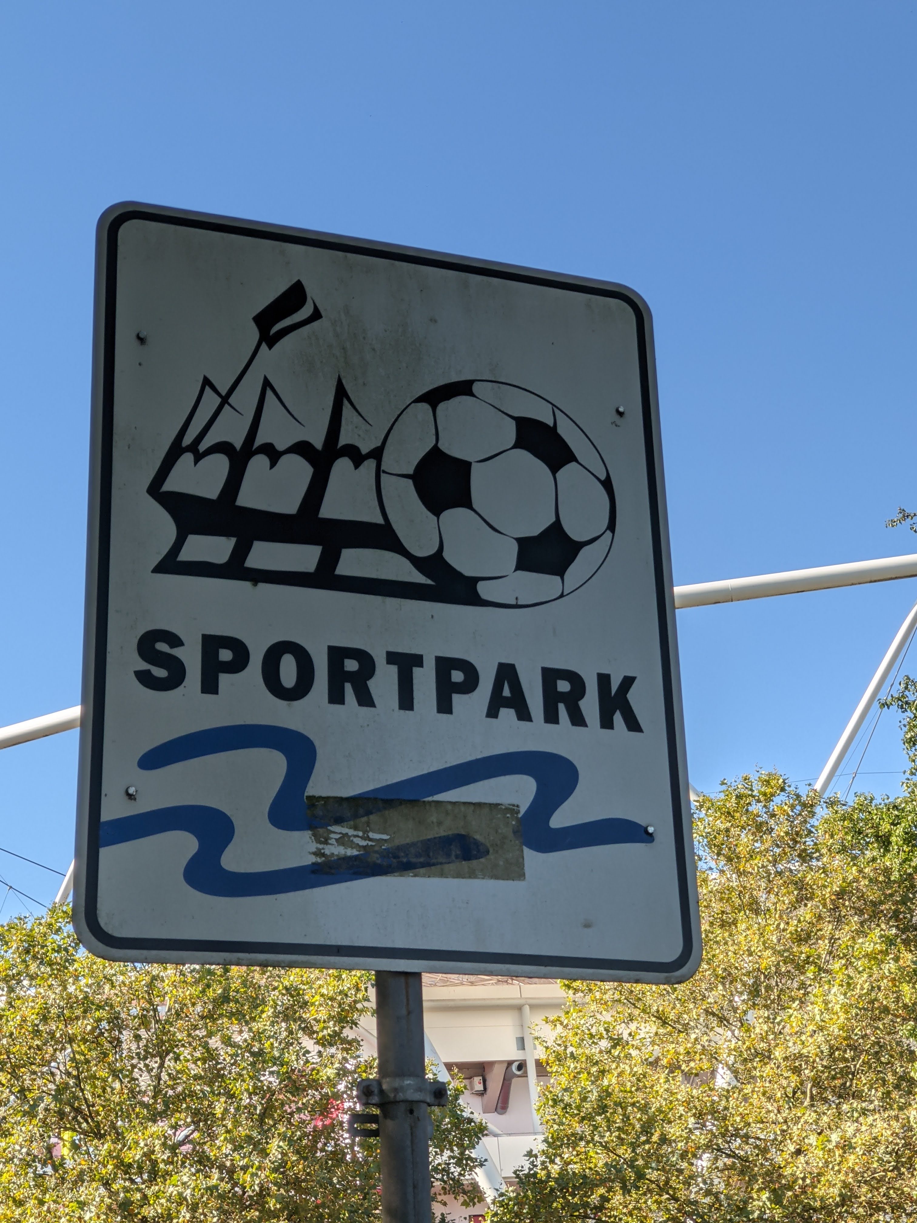 Ein Schild mit dem Schriftzug "Sportpark". Auf dem Schild ist auch ein Stadion und ein Fußball abgebildet.